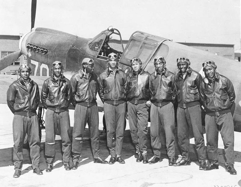 Tuskegee Airmen stand in front of a plane World War II