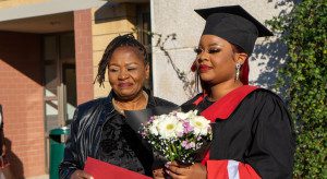 a woman in a graduation gown holding a bouquet of flowers. Photo by Divaris Shirichena on Unsplash.