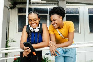 Two Black women students chatting looking at a smartphone