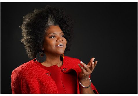 Beloved Dillard felt called to ministry ever since she was a young girl. She received a master’s of divinity at Interdenominational Theological Center in Atlanta, GA, and is in the second year of her doctoral of ministry degree. She is looking into the distance, holding out her hand, wearing large dangling earrings, and a red jacket.