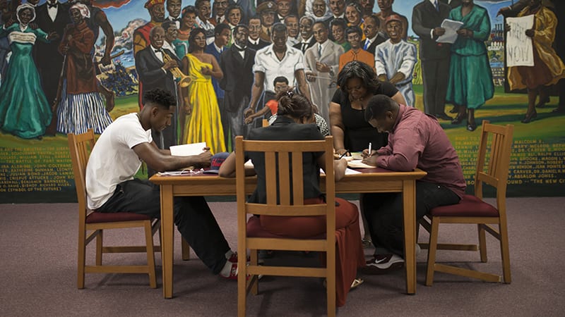 A group of students studying at a table in front of a mural
