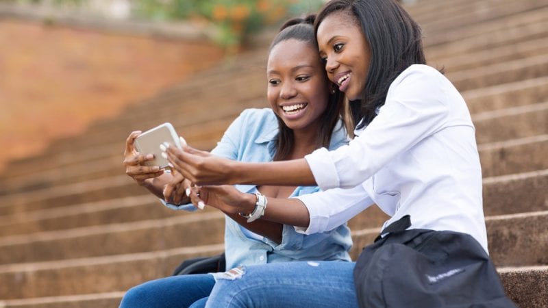 Two female college students talking on a cell phone