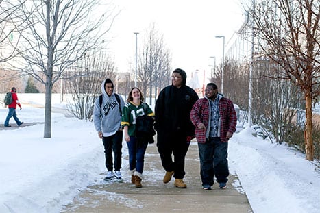 Group of 4 students walking outside on campus in the snow