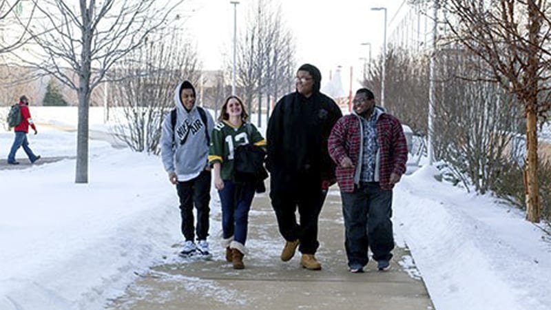 Group of 4 college students walking outside in the snow
