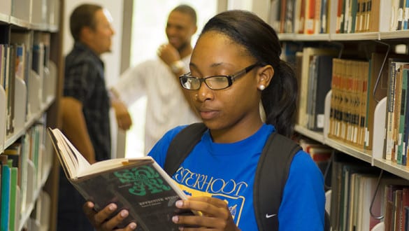 A female Voorhees student reads a book in the campus library