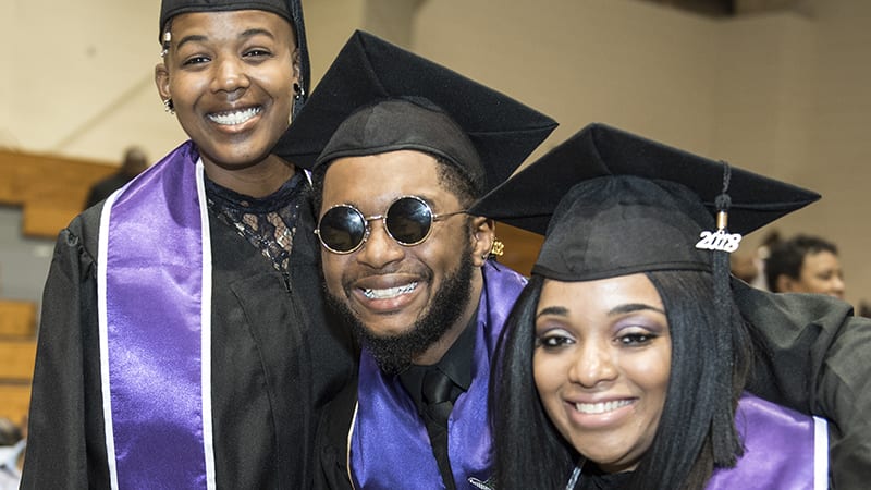 Three Wiley graduates pose and smile for the camera
