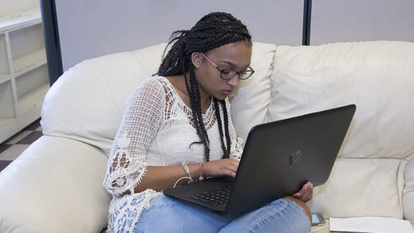 A female Wiley student studying on a laptop